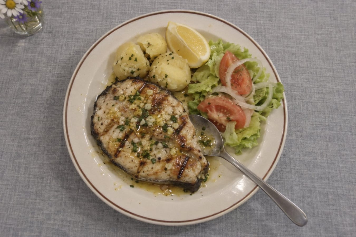 Grilled river fish with garlic butter, potatoes and salad