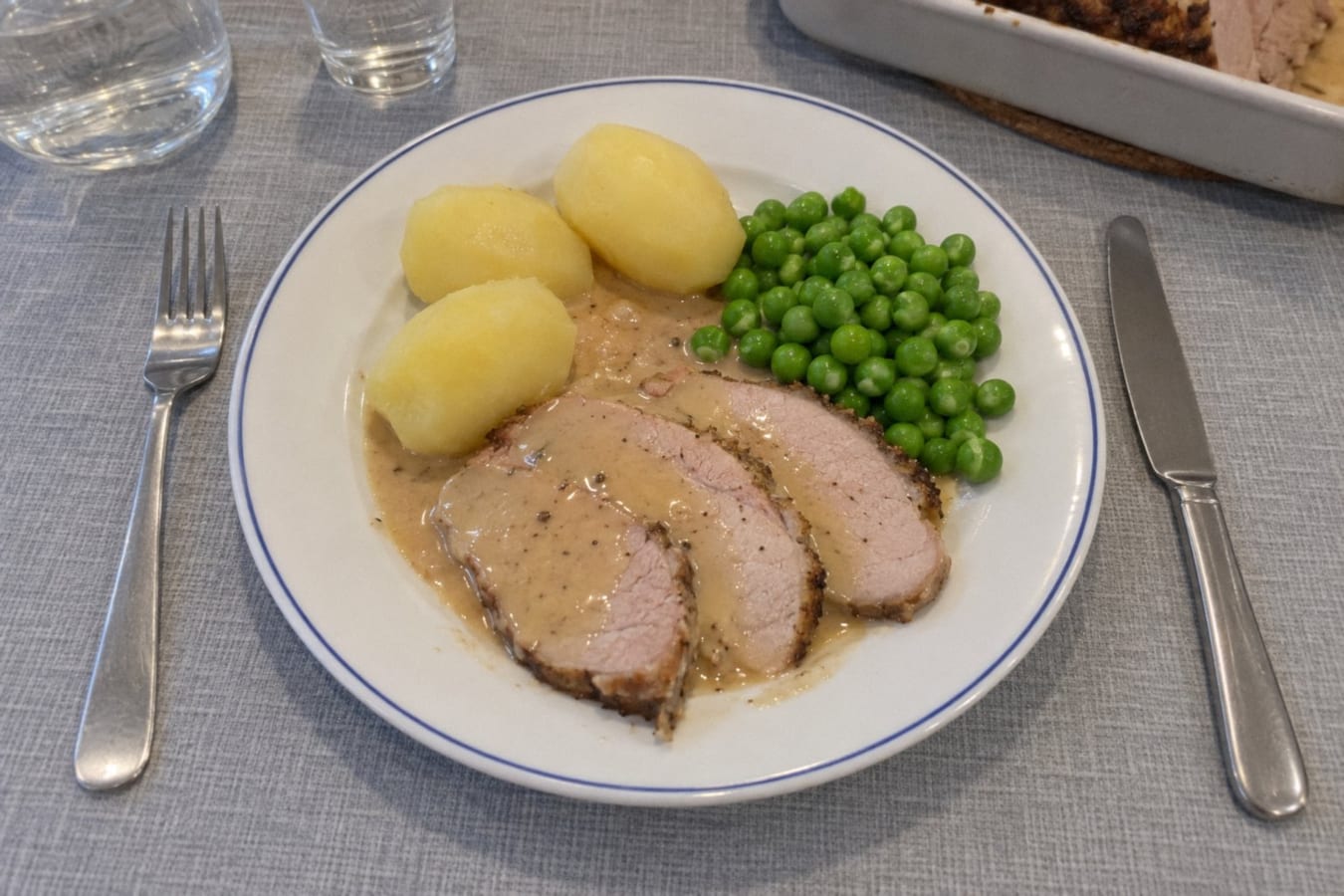 Roast leg of pork with cream sauce, potatoes and peas